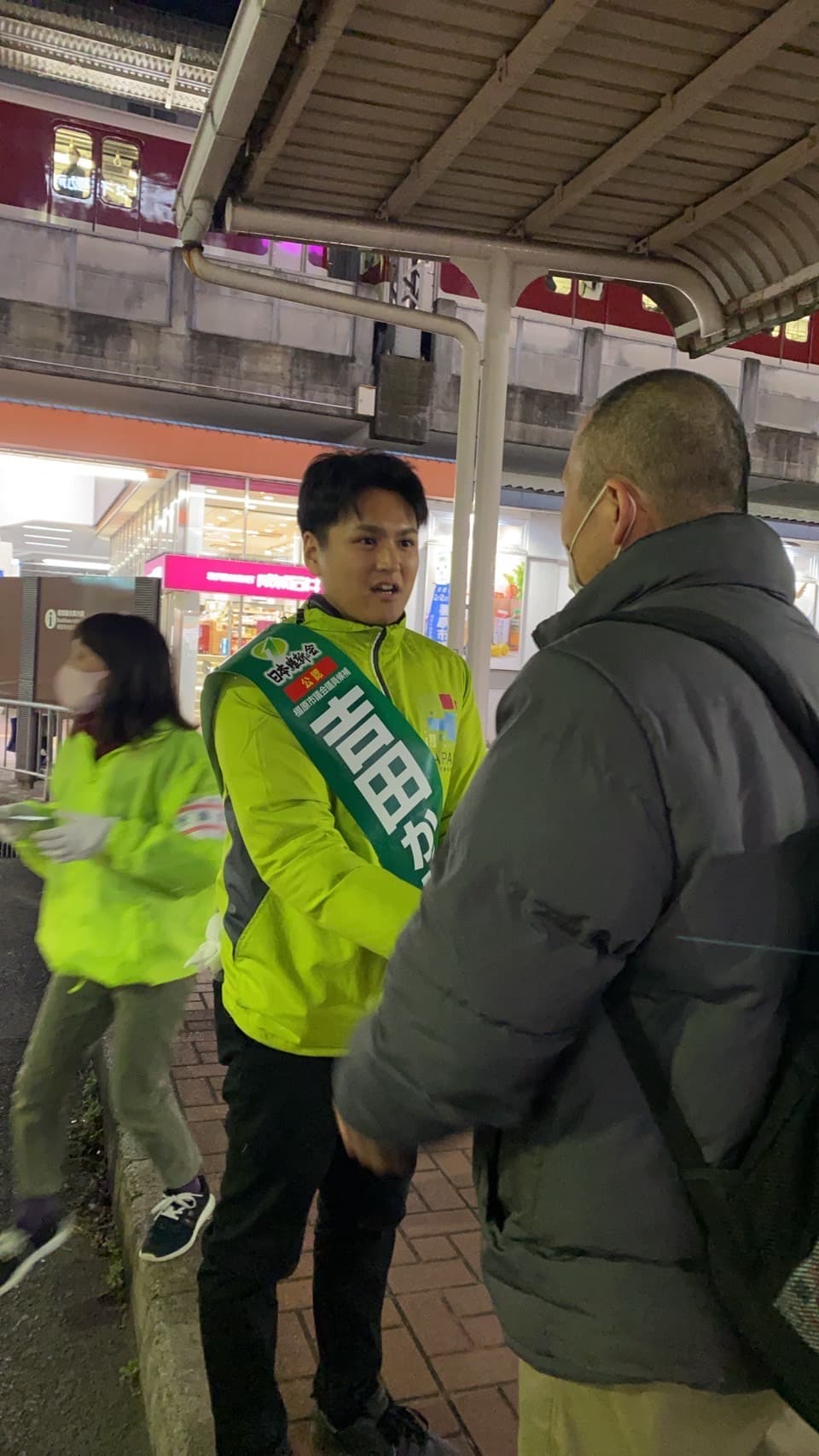 夜の駅前で市民と対話する吉田かずき