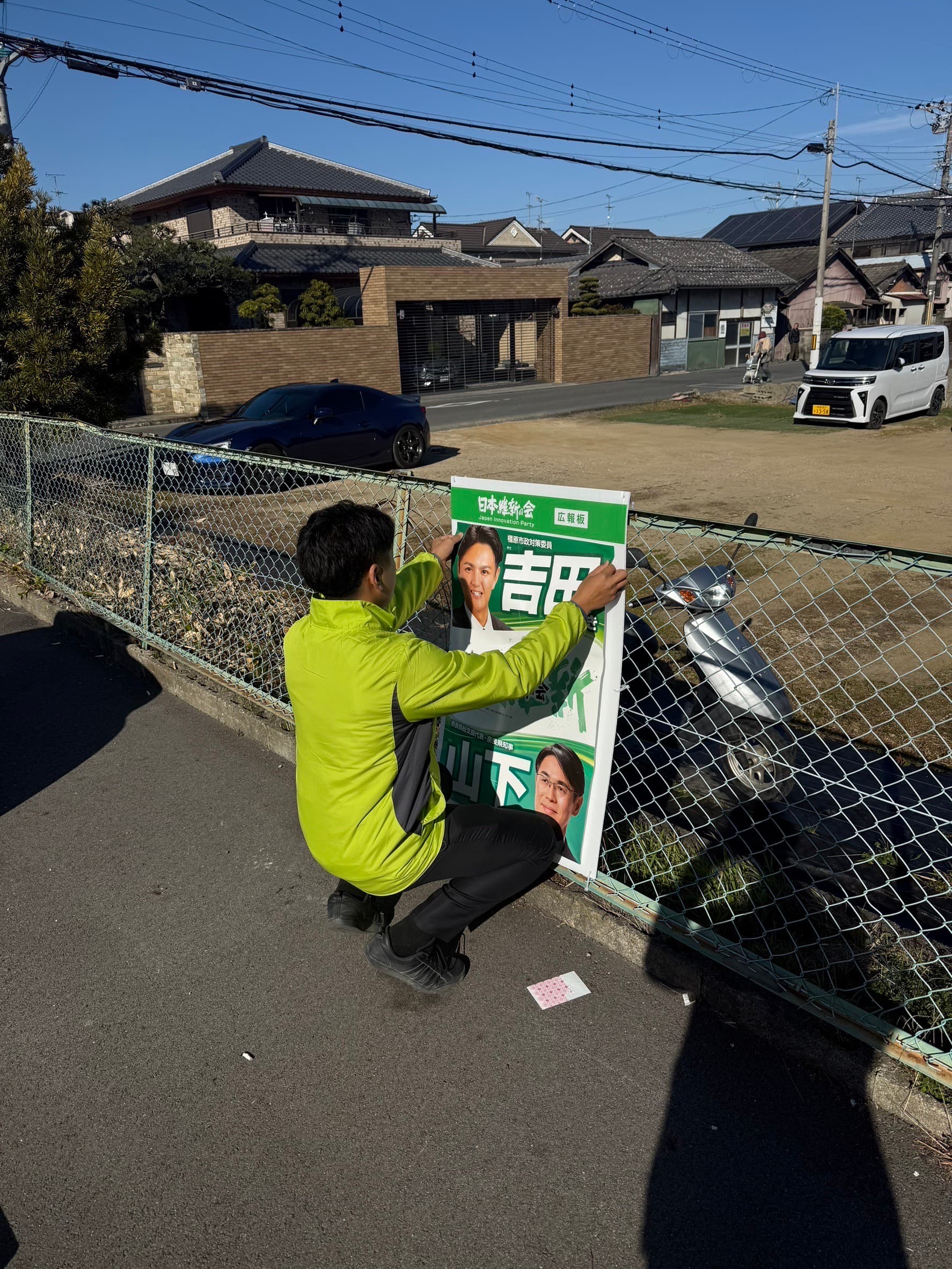 ポスター掲示の作業をする吉田かずき
