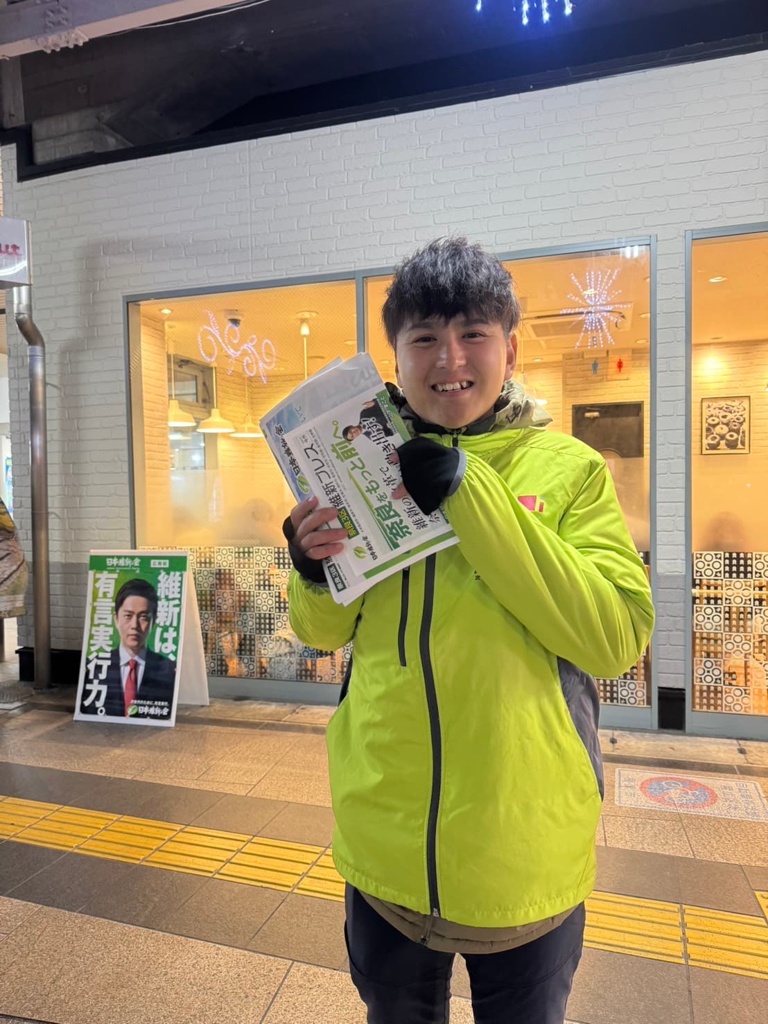 夜の商店街で笑顔の吉田かずき