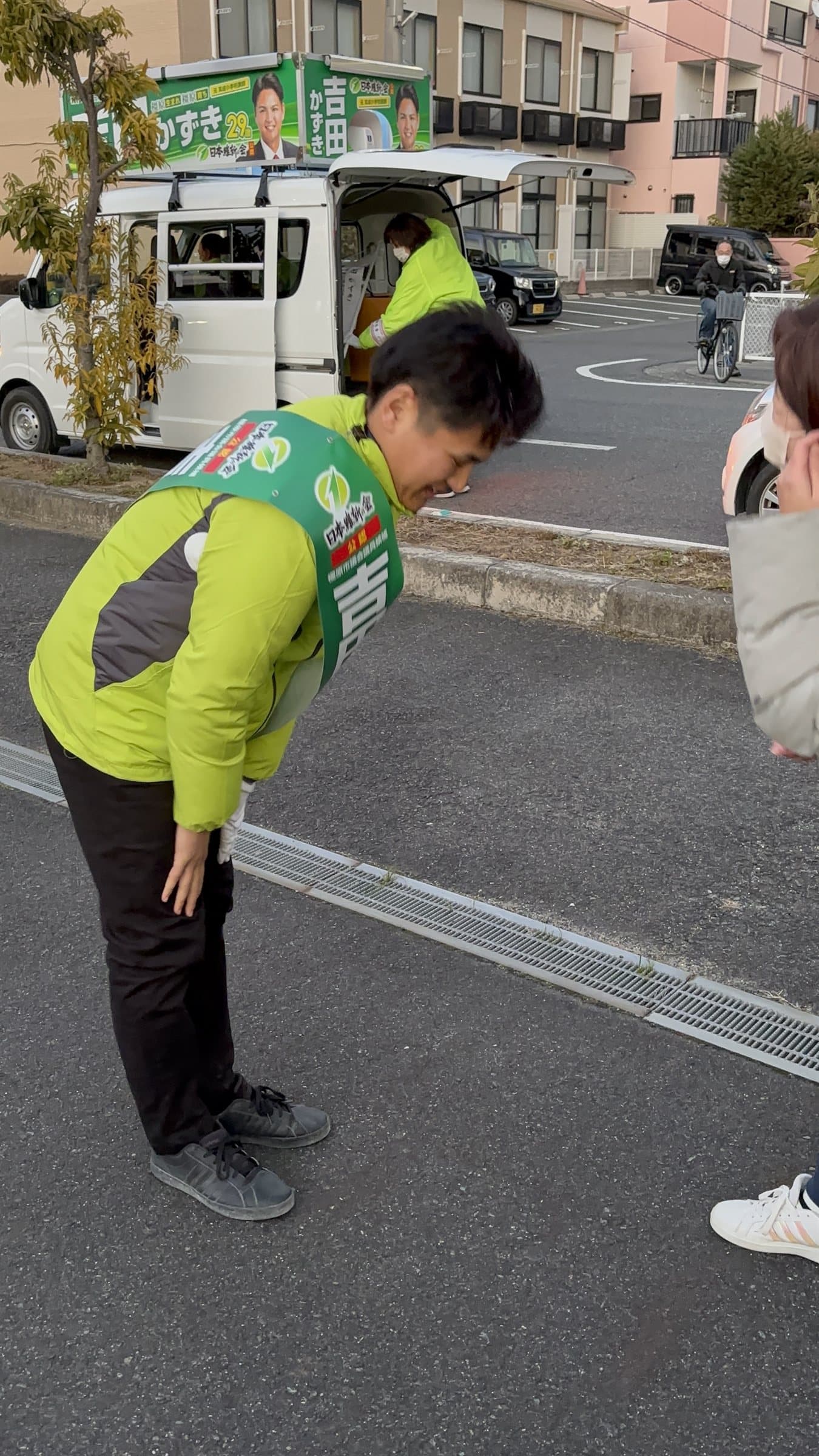 街頭でお辞儀をする吉田かずき